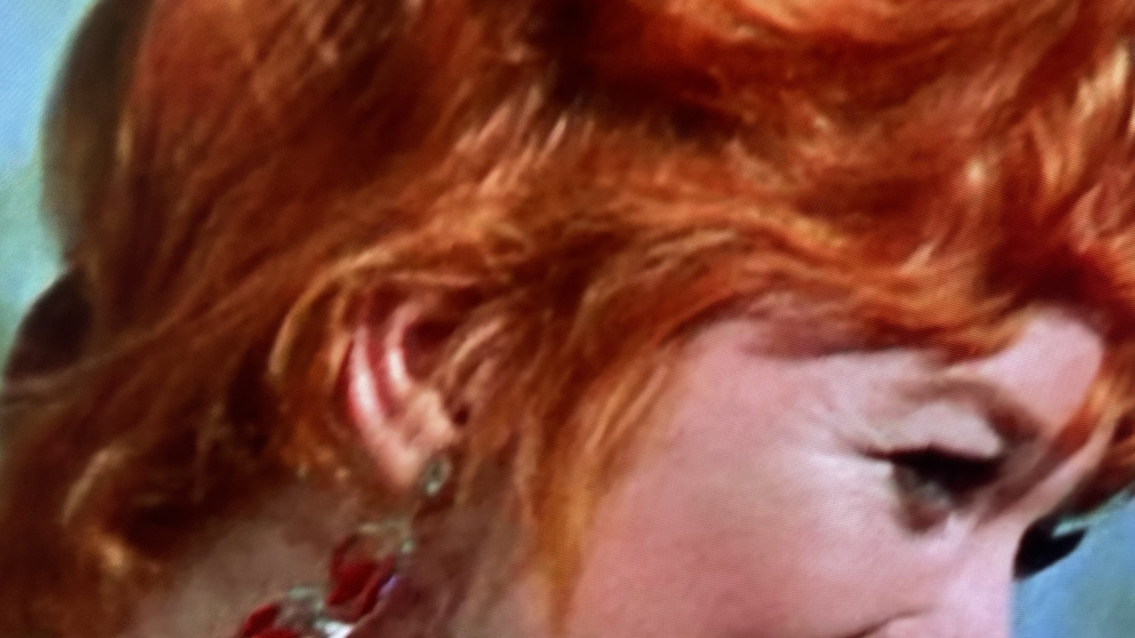 From a screen: a woman in profile with copper-red hair, sixties film colour